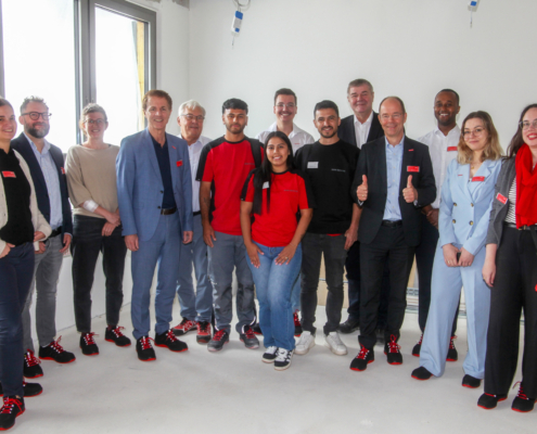 Die drei kolumbianischen Fachkräfte sind auf der Baustelle. Das Foto ist ein Gruppenbild mit Vertreter:innen des FIT for German Climate Businesses-Projekts, der Handwerkskammer Niederbayern-Oberpfalz, des Betriebs DEHN Instatec und natürlich mit den Fachkräften in der Mitte der Gruppe.