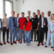 Die drei kolumbianischen Fachkräfte sind auf der Baustelle. Das Foto ist ein Gruppenbild mit Vertreter:innen des FIT for German Climate Businesses-Projekts, der Handwerkskammer Niederbayern-Oberpfalz, des Betriebs DEHN Instatec und natürlich mit den Fachkräften in der Mitte der Gruppe.