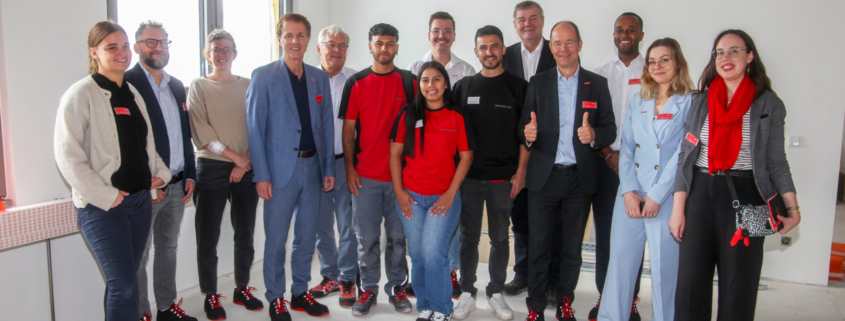 Die drei kolumbianischen Fachkräfte sind auf der Baustelle. Das Foto ist ein Gruppenbild mit Vertreter:innen des FIT for German Climate Businesses-Projekts, der Handwerkskammer Niederbayern-Oberpfalz, des Betriebs DEHN Instatec und natürlich mit den Fachkräften in der Mitte der Gruppe.